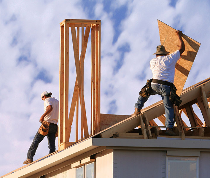 Roofing professionals working on a home under construction